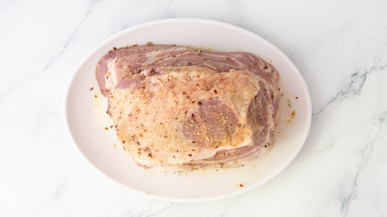 Rubbed and seasoned pork butt on a white platter