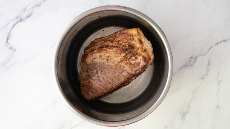 Seared pork butt in a slow cooker pot