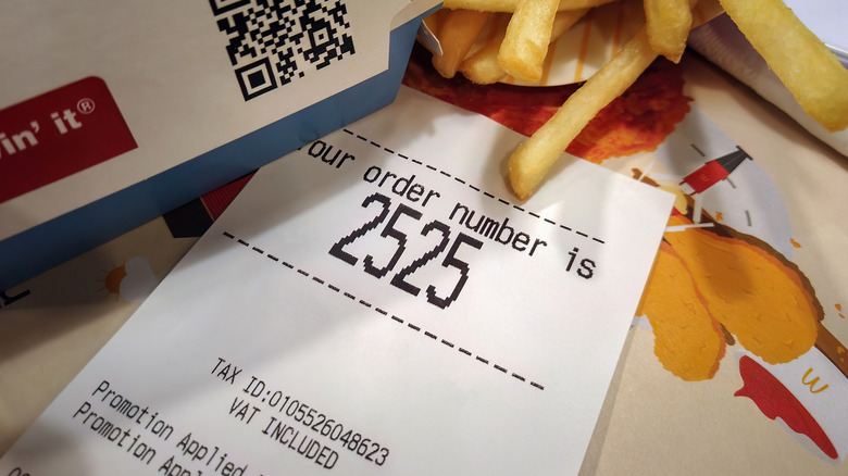 Close up of a McDonald's receipt for order number 2525 sits on a table, surrounded by fries and a burger box.