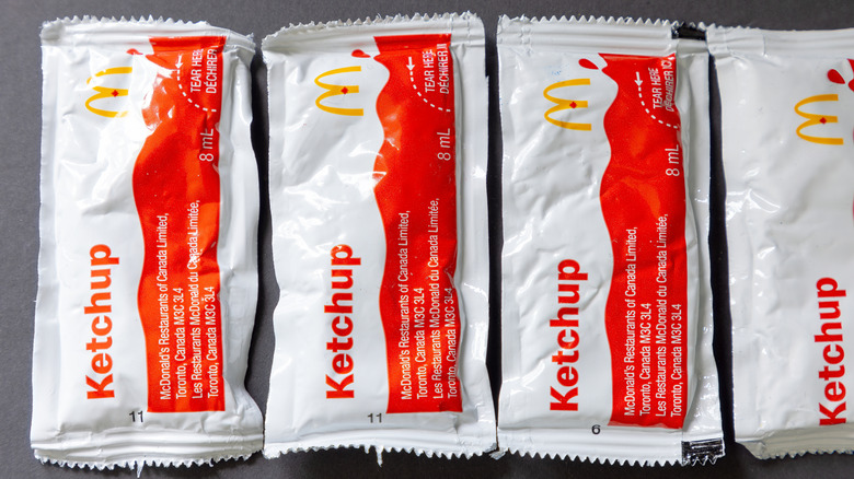 Four McDonald's ketchup packets sit horizontally in a row.