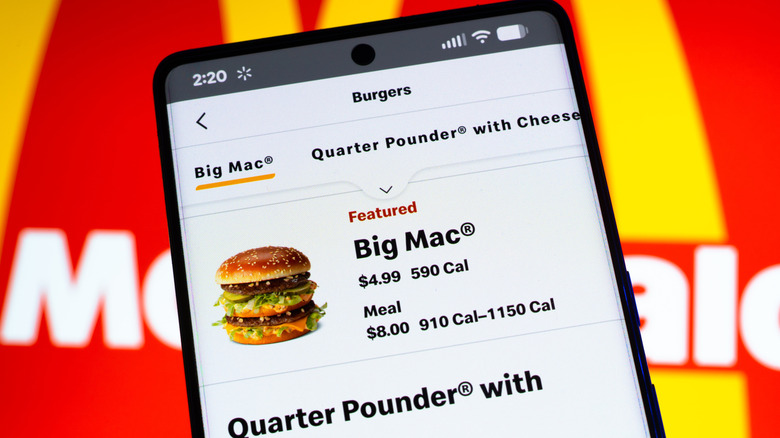 A smartphone with the McDonald's app pulled up, the Big Mac is a featured product shown on the screen. The McDonald's logo is in the background.