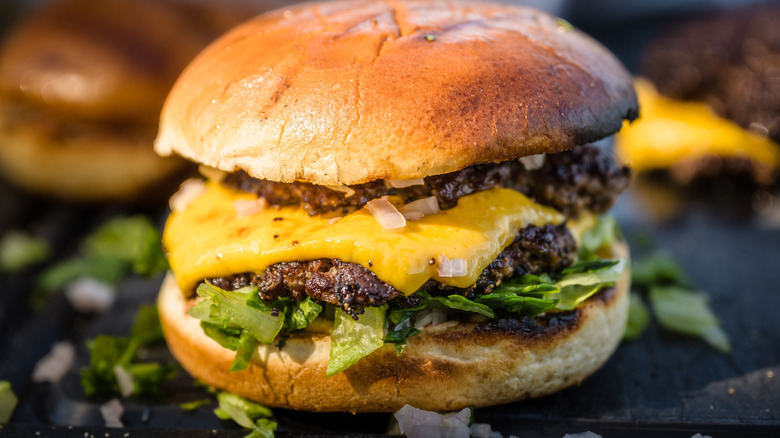 A double smash burger on a bun with cheese, onions, and lettuce