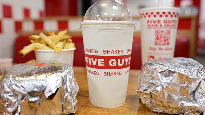 Two burgers from Five Guys alongside two drinks and a small cup of fries