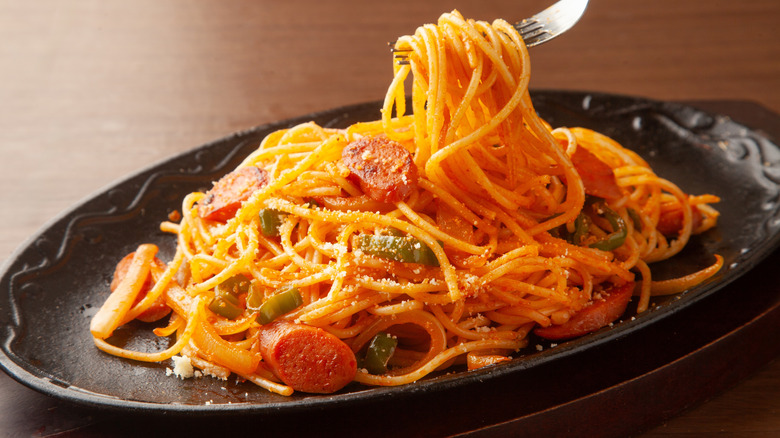 Spaghetti Napolitan with hot dogs on a black plate