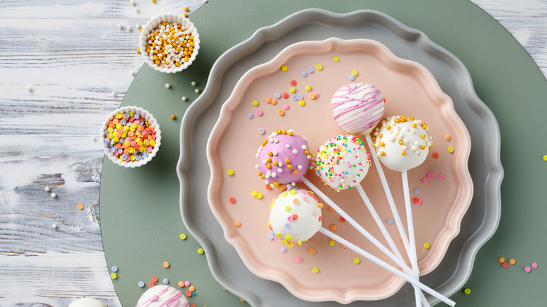 Decorated cake pops on plates with decorations on side