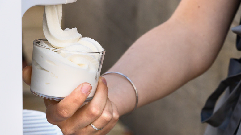worker dispensing soft serve ice cream in a cup