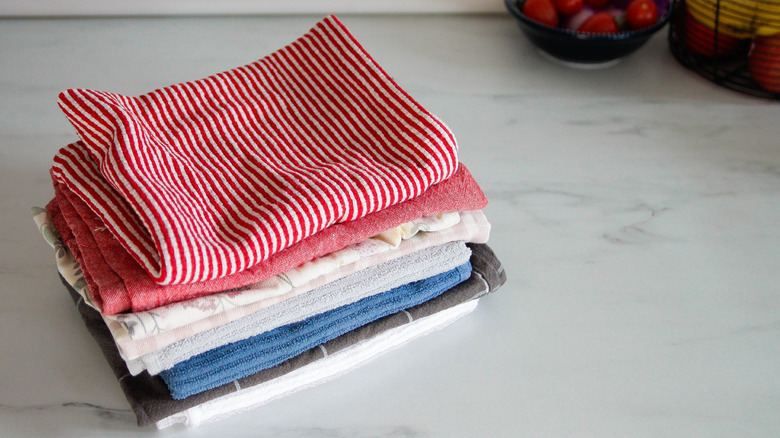 Several kitchen towels stacked on a marble counter