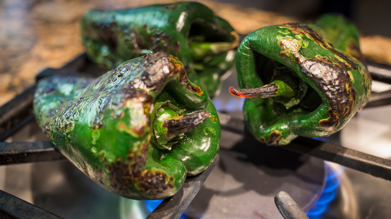 poblano peppers charring on a gas stove burner