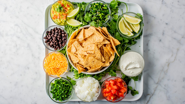 White tray filled with bowls of DIY nacho ingredients