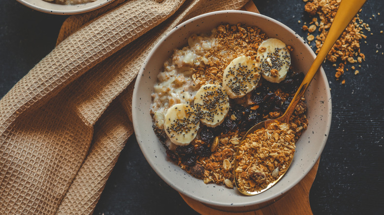 Bowl of oatmeal topped with bananas, chia seeds, and granola