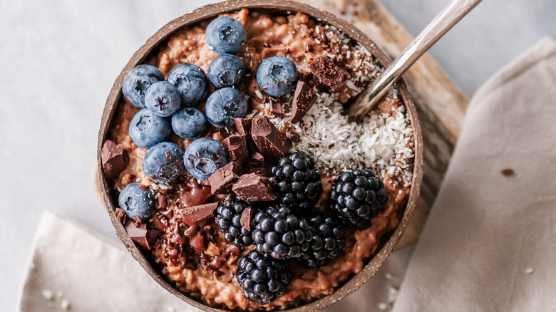 Top view of chocolate oatmeal with blackberries, blueberries, chocolate chunks, and coconut