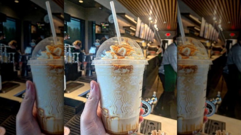 A person holds a Butterbeer Frappuccino in a Starbucks cold cup