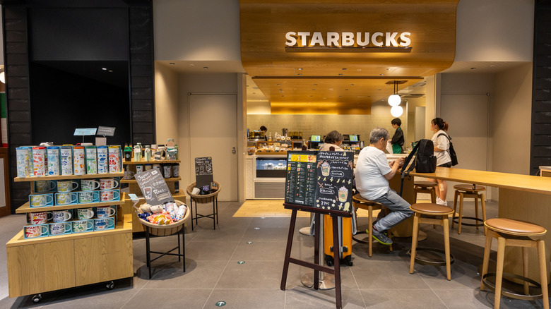 Interior of a Starbucks cafe with customers sitting at the tables and workers behind the counter