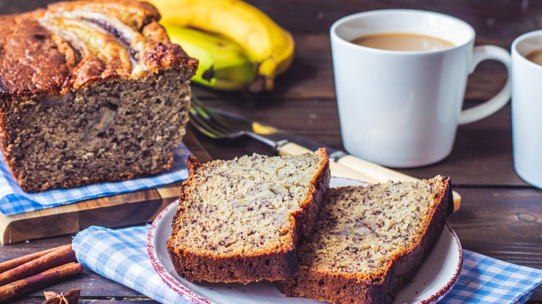 Banana bread and a cup of coffee sitting on a rustic wood table.