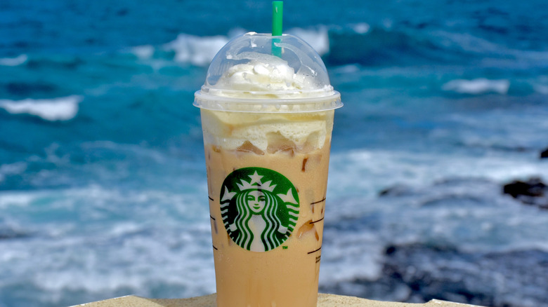 Starbucks iced macchiato on a table in front of the ocean.