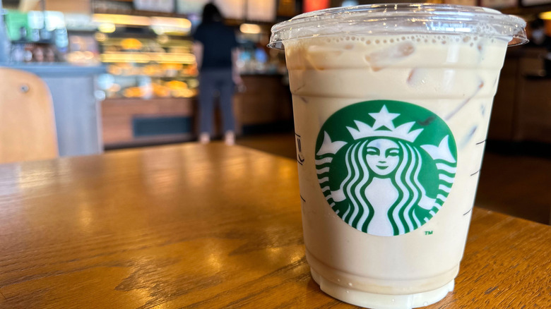 An iced latte in a plastic cup inside of a Starbucks location