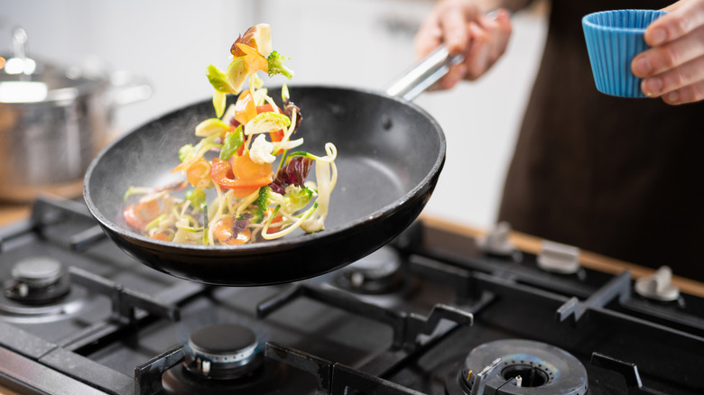 Person sauteing vegetables in a pan