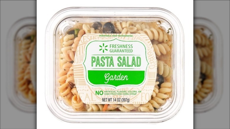 Clear plastic tub of Freshness Guaranteed Garden Pasta Salad on white background