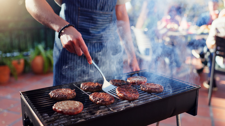 person cooking burgers on a grill