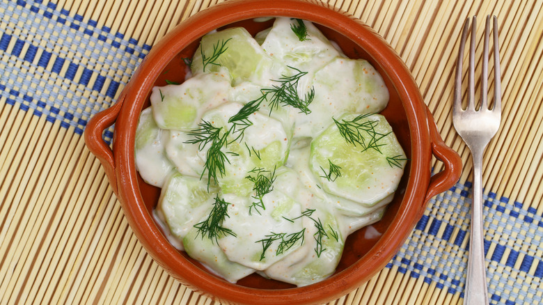 Top view of creamy cucumber salad with sprigs of dill
