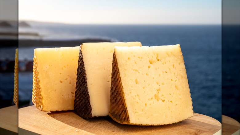 Assortment of three Spanish hard cheeses on wooden board