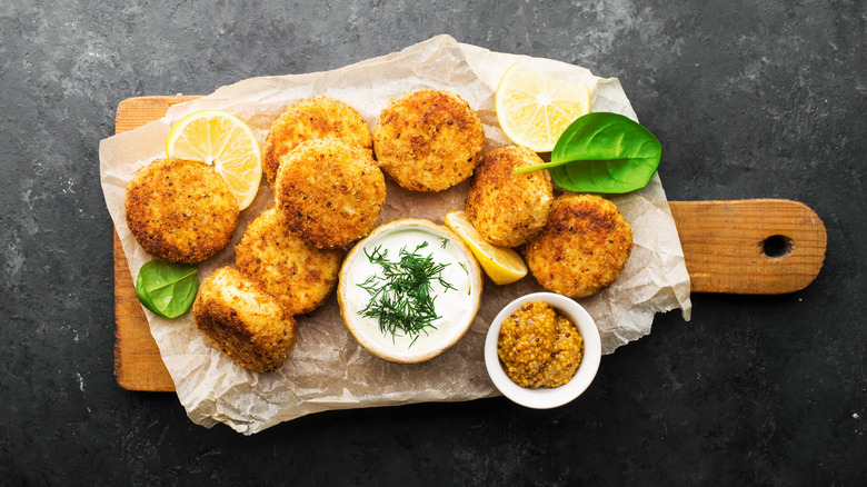 Cooked tuna patties with tartar sauce on wooden board