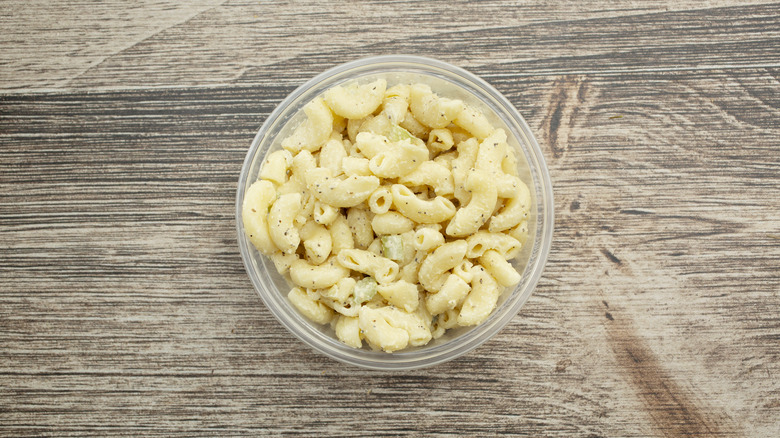 Top view of a round plastic container with macaroni salad inside