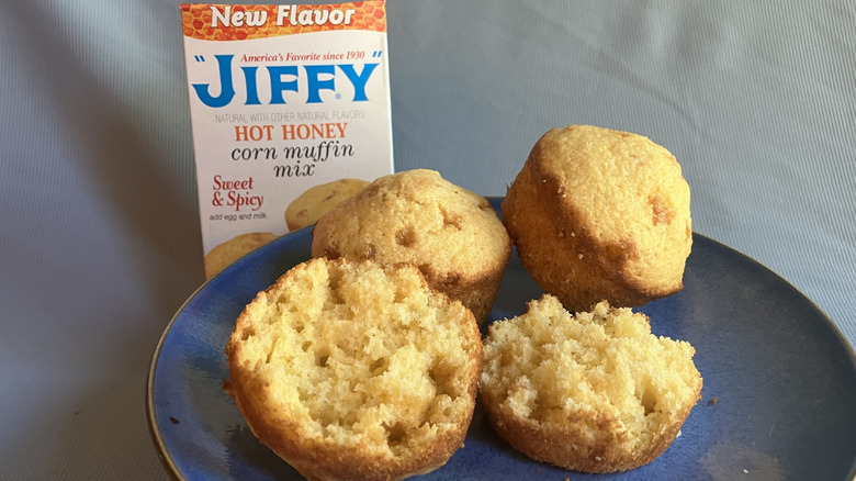 A plate of spotted Jiffy Hot Honey corn muffins with the box of mix in the background.