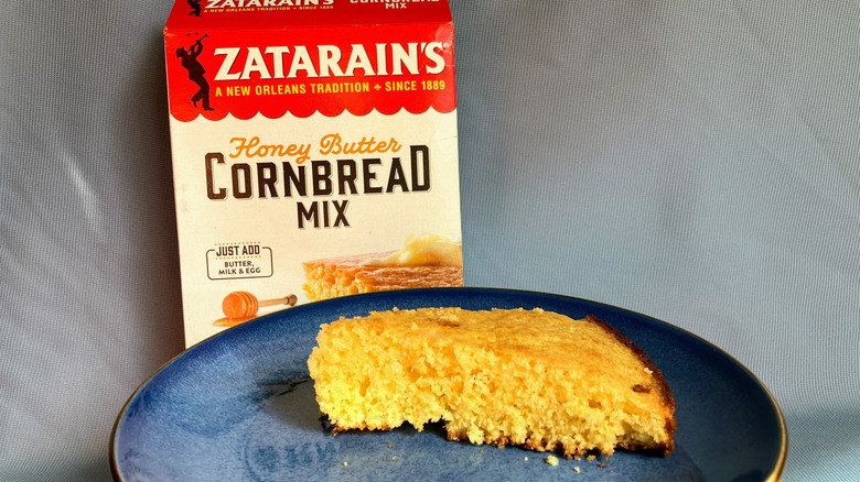 A slice of Zatarain's cornbread on a blue plate with the cornbread mix box in the background.