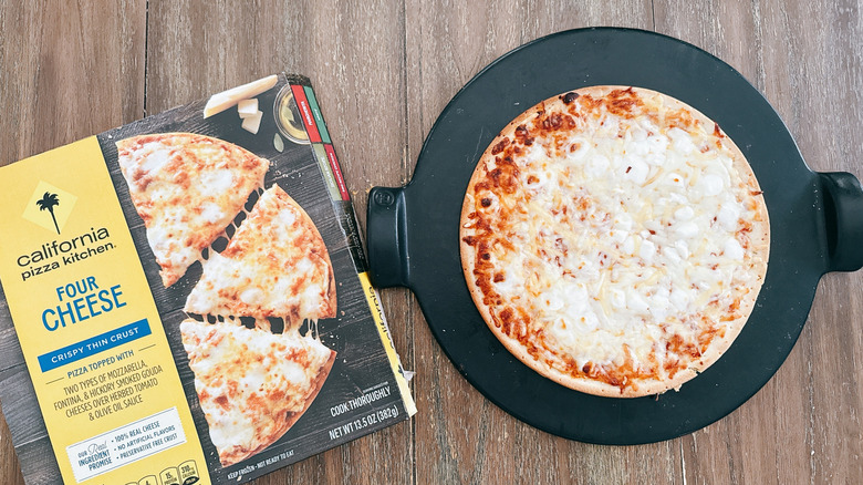 California Pizza Kitchen crispy thin crust four cheese frozen pizza next to box on wooden table