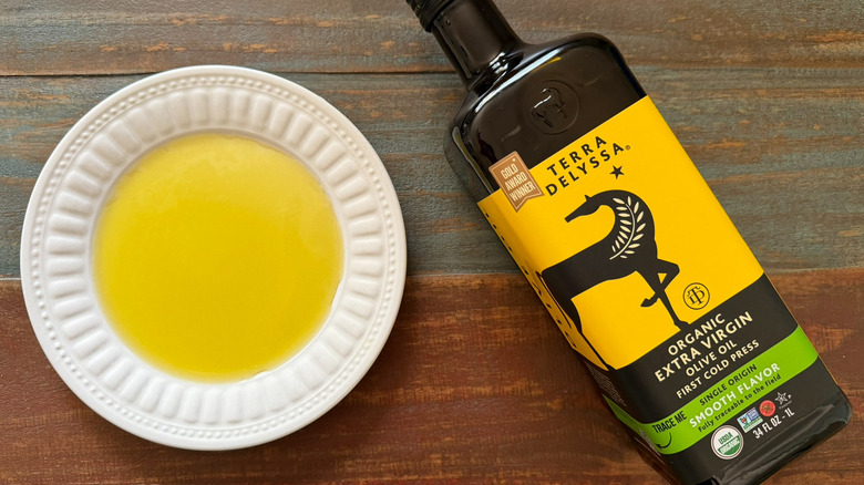 Terra Delyssa Organic Extra Virgin Olive Oil bottle next to a dish with oil