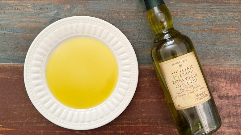 Trader Joe's Sicilian extra virgin olive oil bottle next to a dish with oil