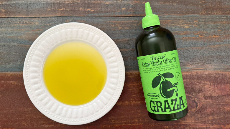 Graza Drizzle Extra Virgin Olive Oil bottle next to a dish with oil