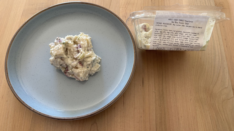 potato salad on blue plate next to plastic container of potato salad