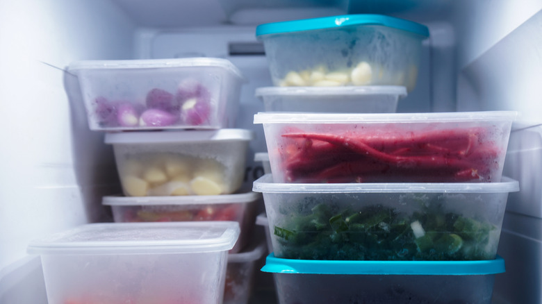 Assorted veggies divided in plastic containers in freezer