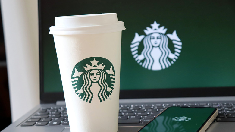 A Starbucks cup with a phone both showing the Starbucks logo