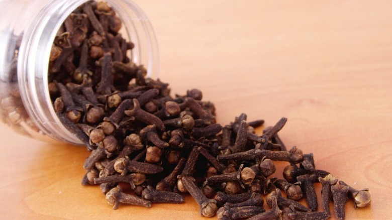 Cloves spilling out of a glass jar.