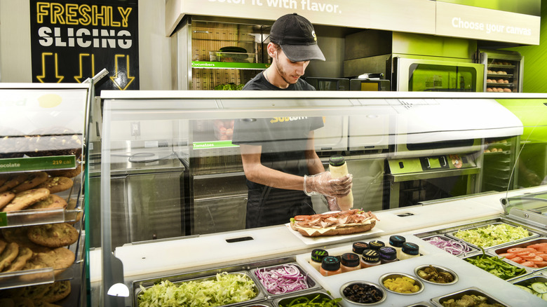 A Subway worker preparing a sandwich.