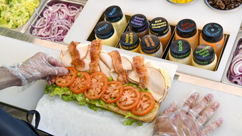 A Subway worker builds a sandwich behind the counter