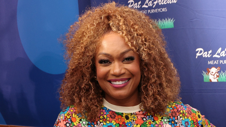 Sunny Anderson smiles in bright flowered dress