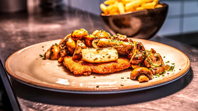 Plate with fried meat with sauteed mushrooms on top