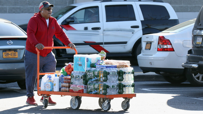 man pushing flat full of bulk groceries