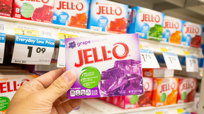 Someone selecting a box of grape flavored Jell-O at a store