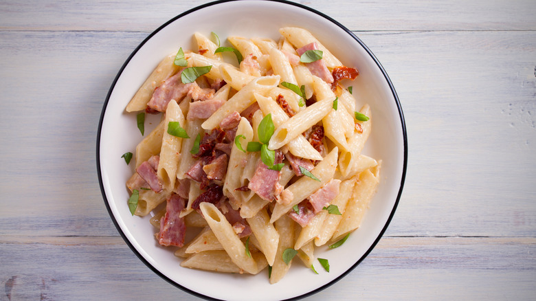 Penne pasta with fresh basil, ham, and sun-dried tomatoes