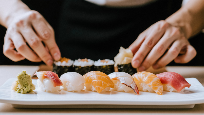 Sushi chef hands preparing nigiri platter