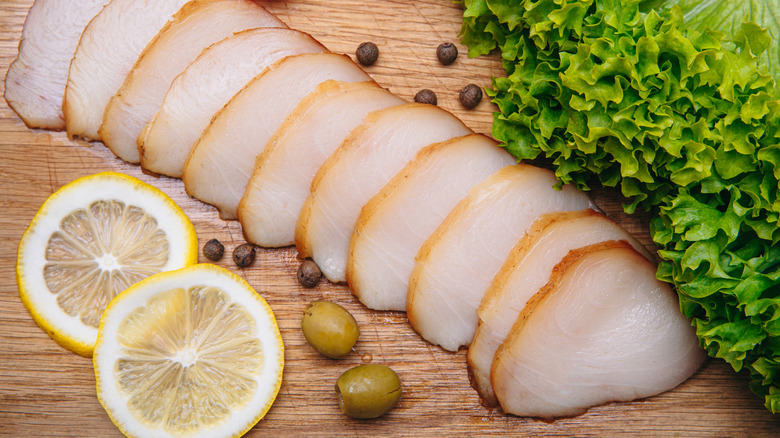 Fileted escolar fish on wooden table by lemons and lettuce