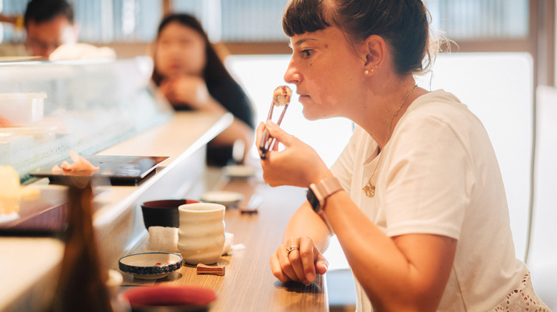 Woman sniffs a sushi roll in a Japanese restaurant