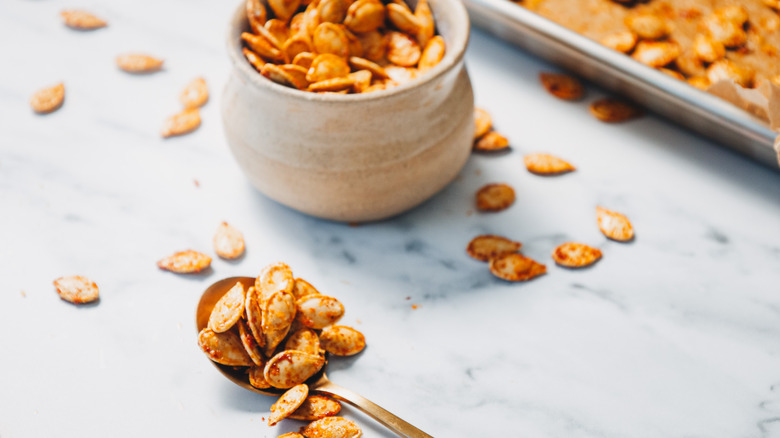 Small spoonful of pumpkin seeds, next to small bowl
