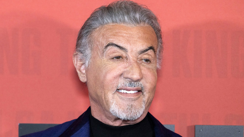 Sylvester Stallone smiles in a blue suit at an event