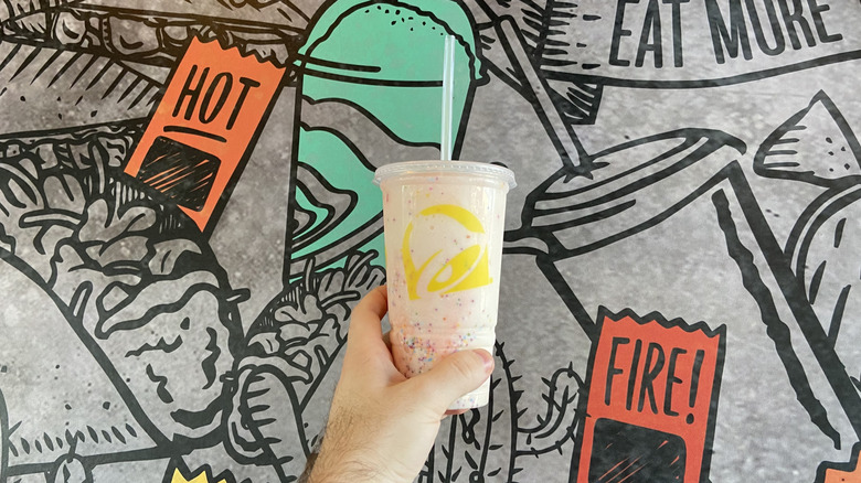 hand holding the Confetti Cookie Freeze in front of a Taco Bell mural